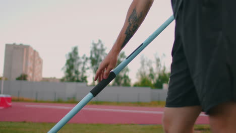 Primer-Plano:-Mano,-Un-Atleta-Masculino-En-El-Estadio-Toma-Una-Jabalina-Para-Lanzar-Y-Se-Prepara-Para-Lanzar.-Va-Toma-La-Lanza.-Entrenamiento-De-Un-Lanzador-De-Jabalina